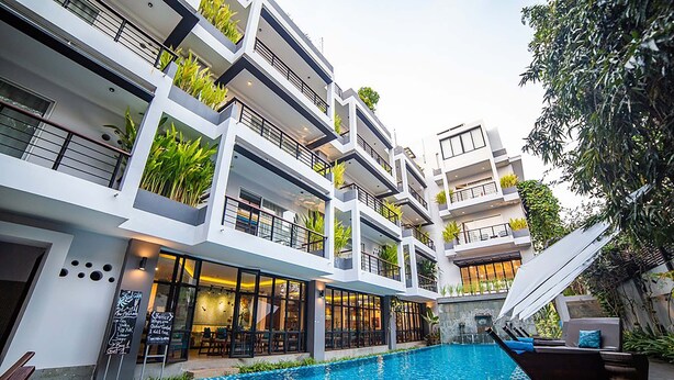 A modern hotel with a central swimming pool, multiple balconies with plants, and a restaurant with outdoor seating. - Riversoul Boutique (Siem Reap)