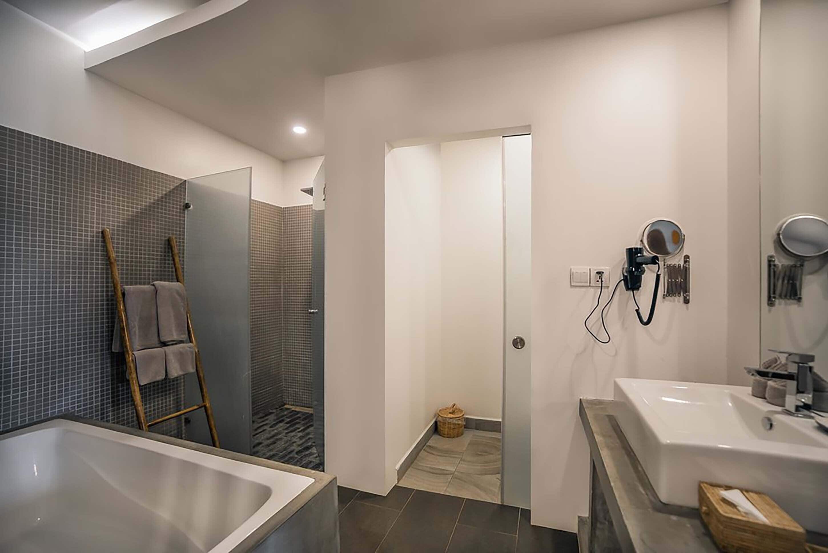 Un baño moderno con una bañera grande, zona de ducha e inodoro con lavabo.