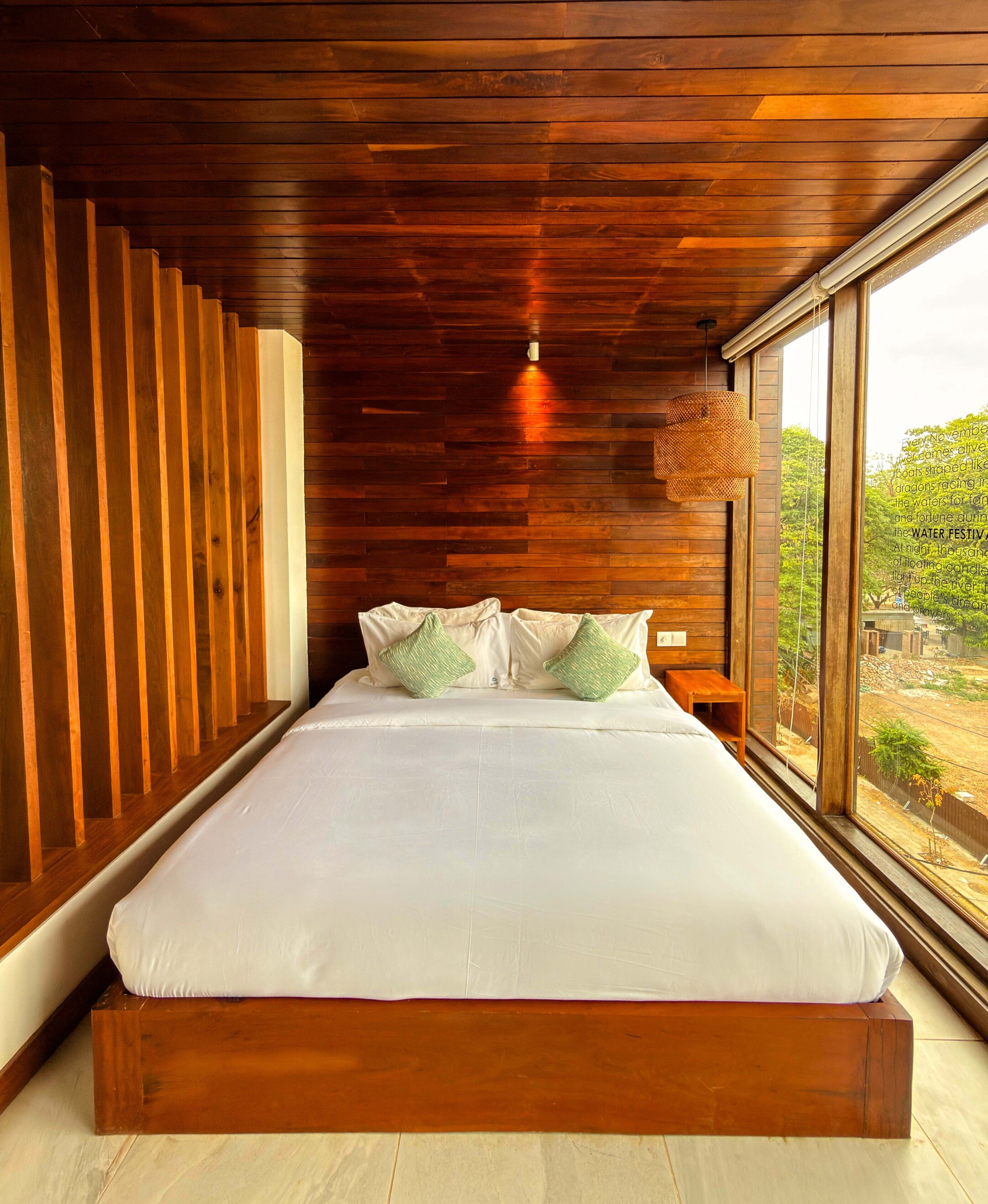 Ein Schlafzimmer mit Holzboden, einem großen Fenster und einem Bett mit weißer Bettwäsche.