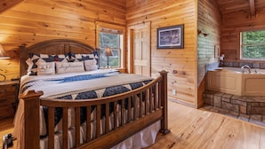 Une chambre à coucher dans une cabane en bois, avec un lit, une fenêtre, un tableau encadré et une salle de bain avec une baignoire.