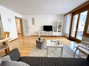 Un salon moderne comprenant un canapé, une table basse, un téléviseur et une bibliothèque.