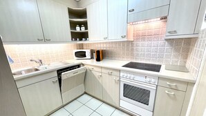 Een keuken met witte kastjes, een magnetron, een broodrooster, een spoelbak en een oven.
