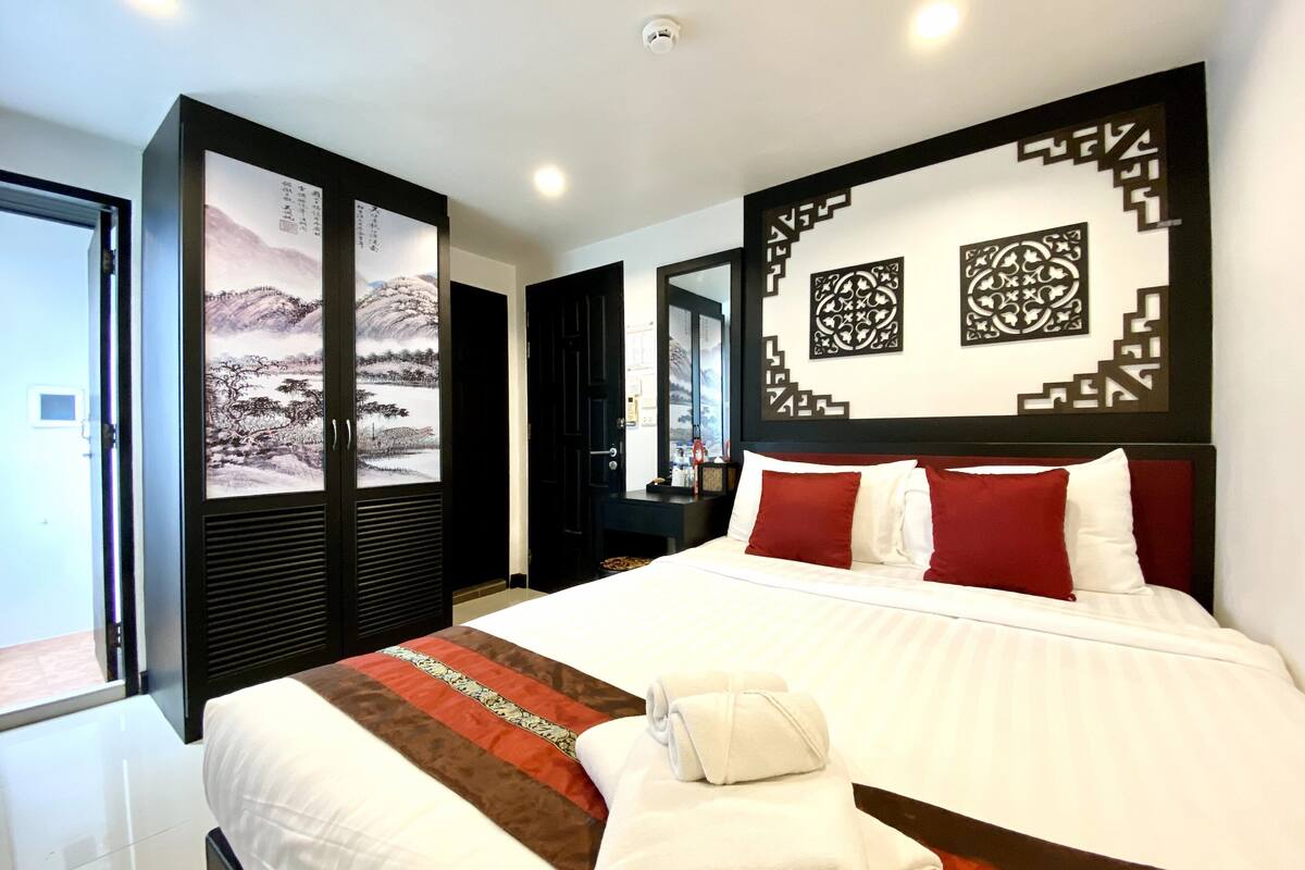 A hotel room with a large bed, a view of the outside, and a decorative wall panel.