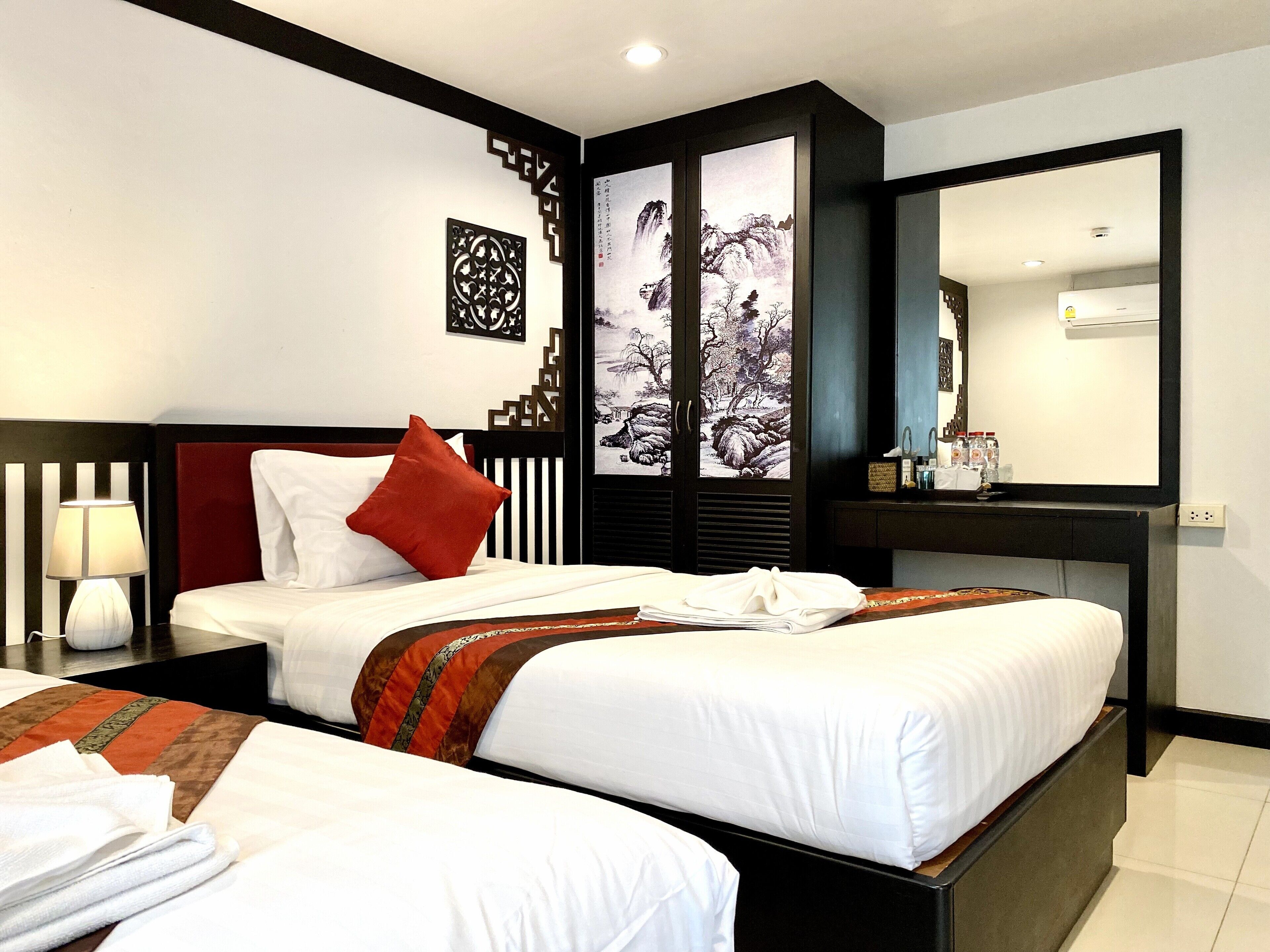 A hotel room with two beds, a desk with a mirror, and a wall with decorative panels.
