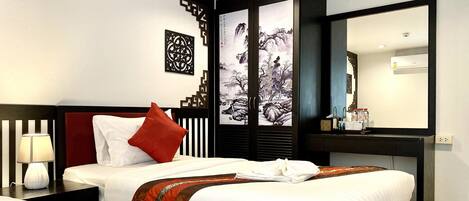 A hotel room with two beds, a desk with a mirror, and a wall with decorative panels.