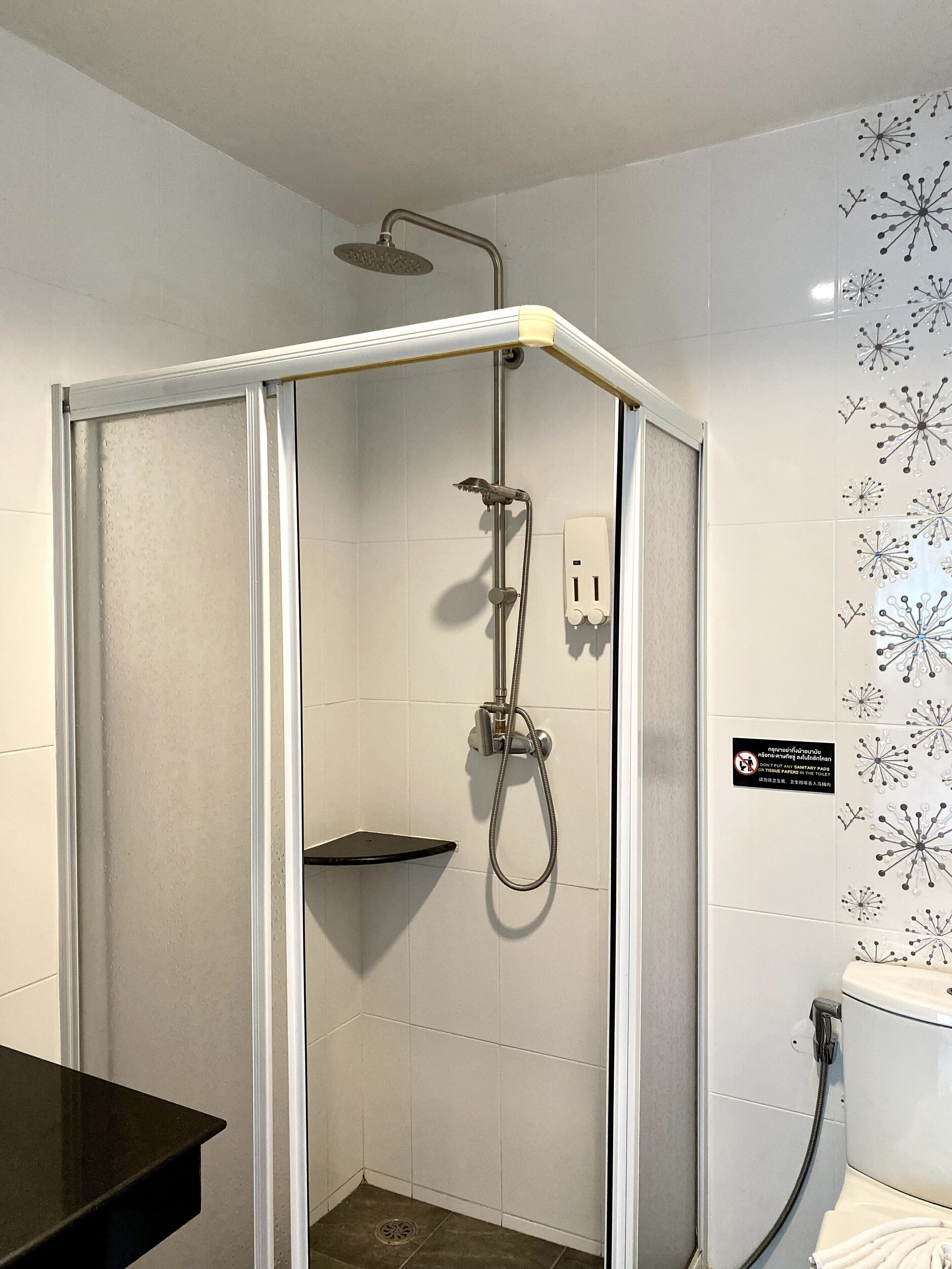 A shower with a handheld showerhead and a wall-mounted faucet.
