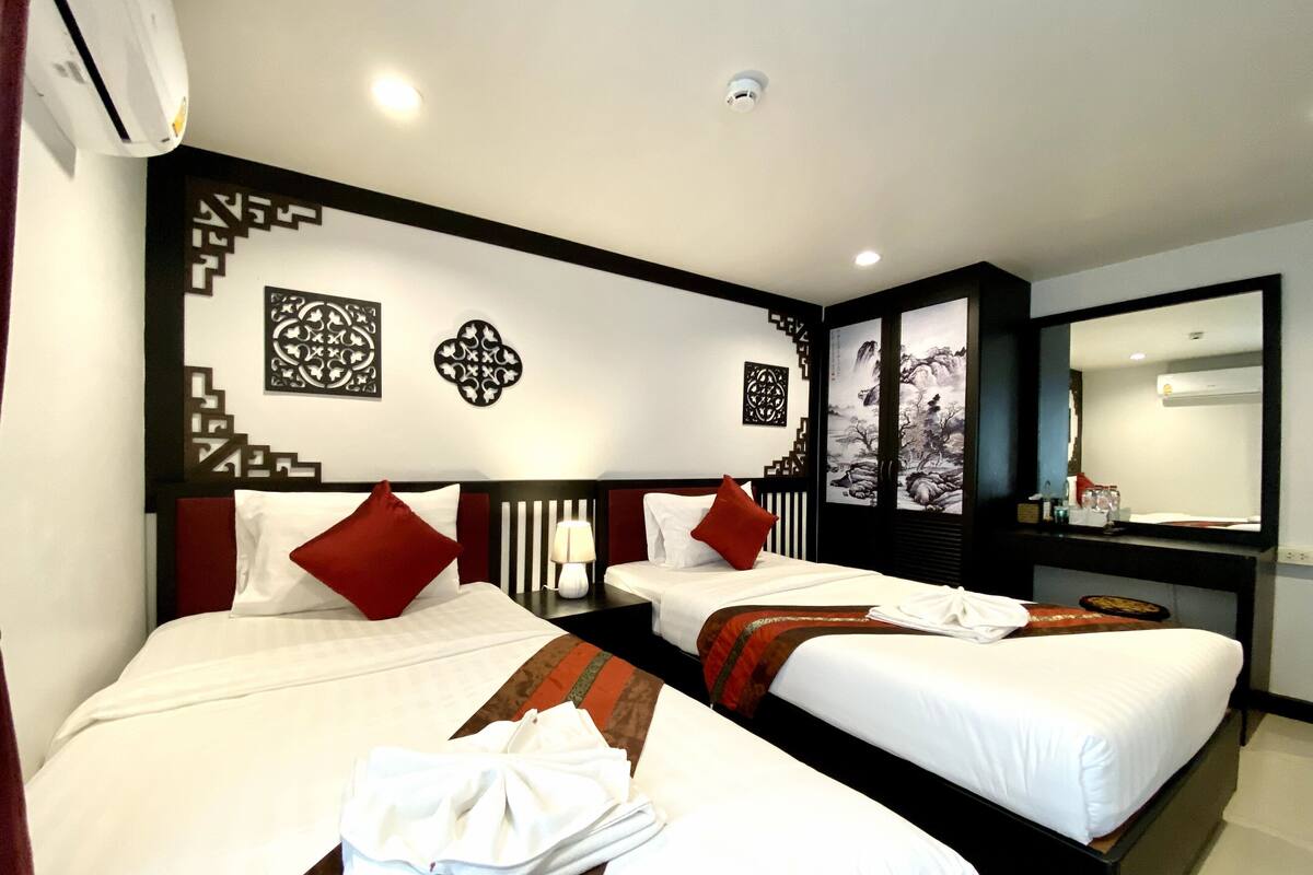 A hotel room with two beds, a desk, and a large mirror.