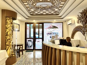 A reception area with a wooden reception desk, a decorative wall piece, and a patterned floor.