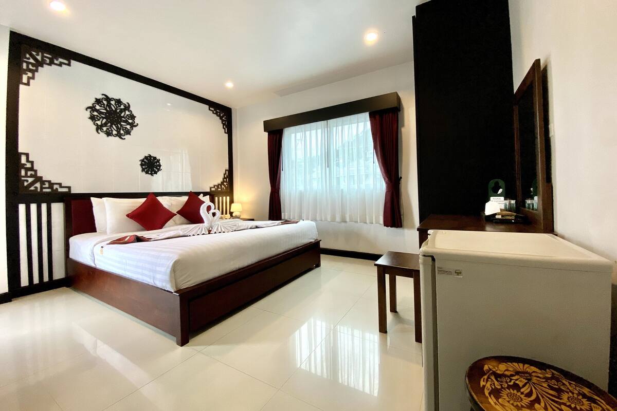A hotel room with a bed, bedside table, and a desk with a chair.