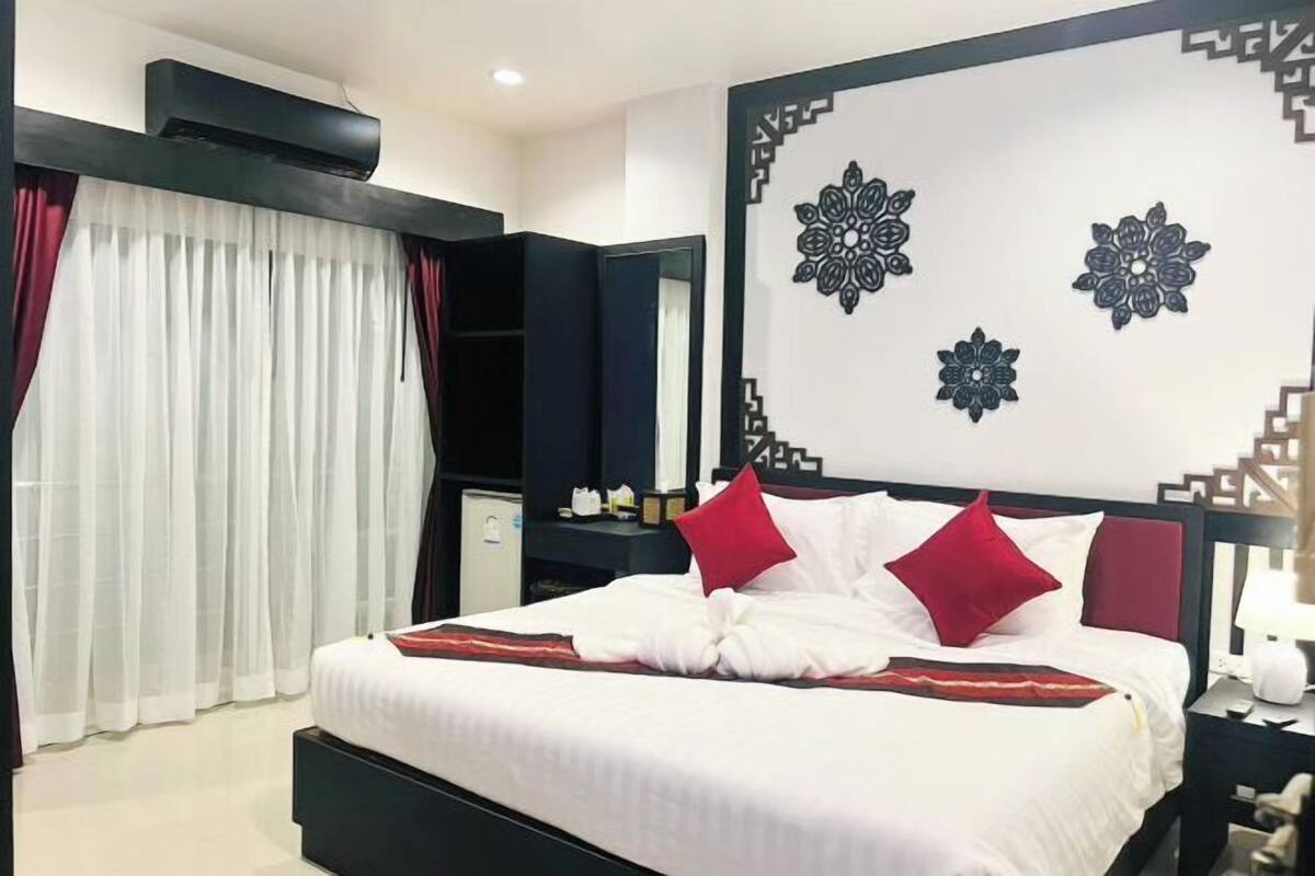 A hotel room with a bed, a large mirror, a wardrobe, and a decorative wall panel.