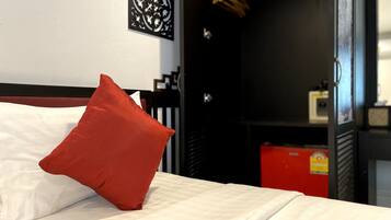 A bed with white bedding and a red pillow, a black headboard, and a wall with a decorative panel.