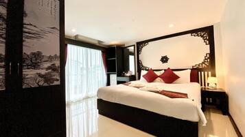 A modern hotel room with a large bed, a nightstand, a wall-mounted TV, and a large window with sheer curtains.
