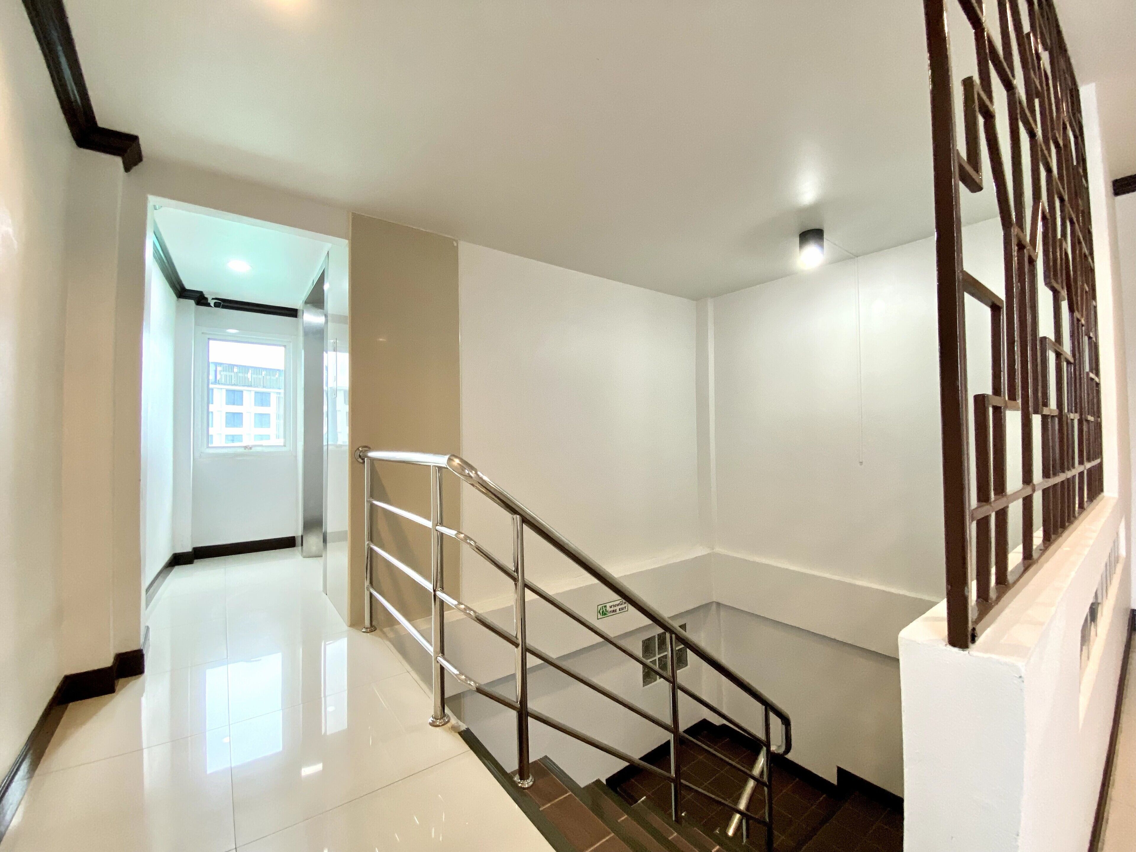Una escalera moderna con barandillas de metal, un interior blanco e impecable y vistas a otra habitación.