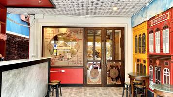 A restaurant with a red and yellow facade, a tiled floor, and a ceiling with a geometric pattern.