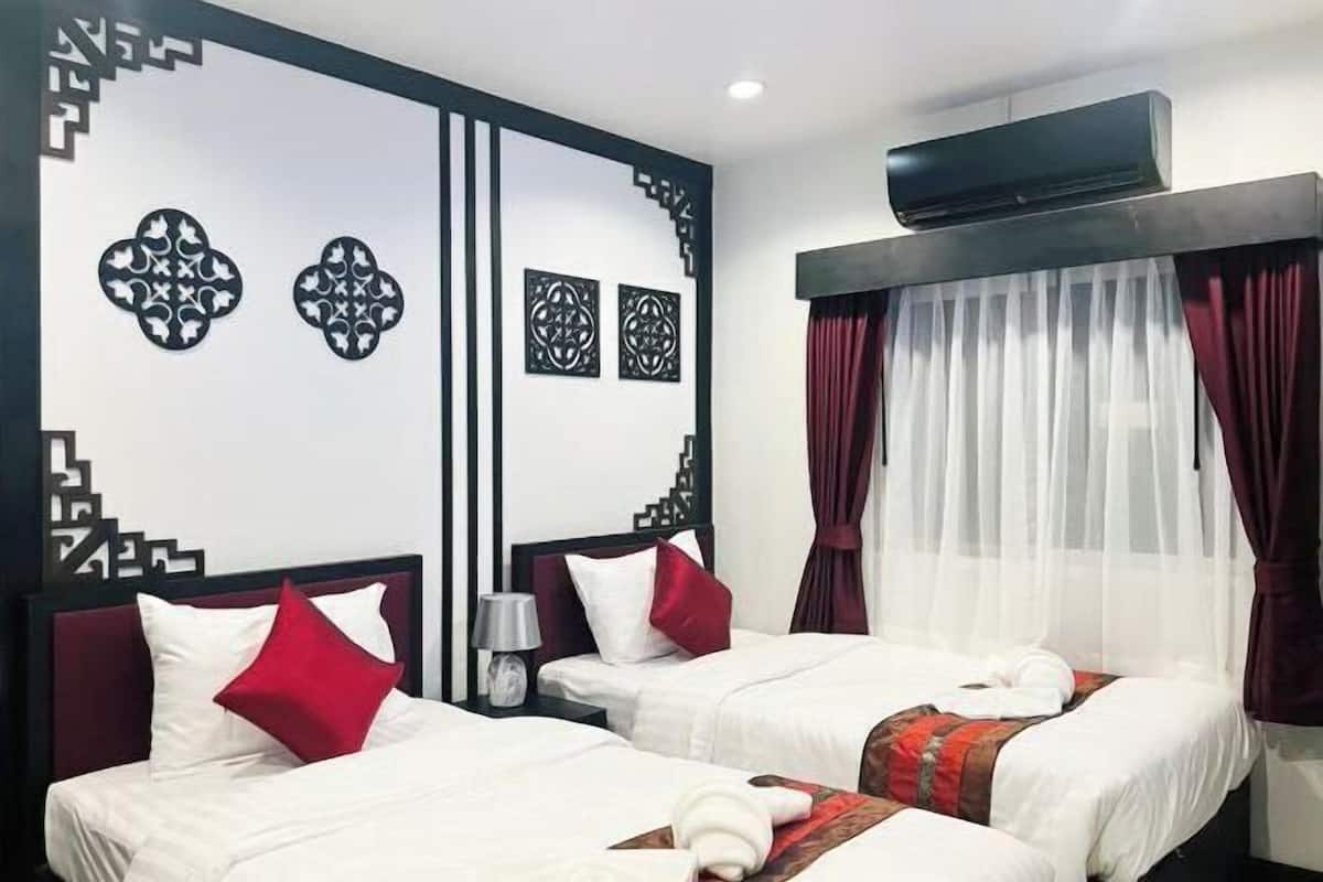 A hotel room with two beds, a wall-mounted air conditioner, and a window with sheer curtains.