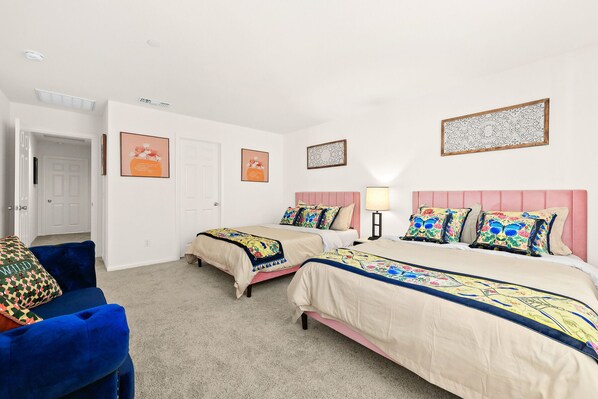 A hotel room with two beds, a blue armchair, and a door leading to another room. - New Townhouse/3BD/2.5BA (Chino)