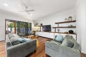 Relax in this stylish living room with a ceiling fan, TV, and comfortable seating area, perfect for unwinding or socializing.