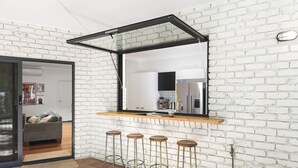 Uma cozinha moderna com parede de tijolos brancos, um espelho grande e um espaço com banquetas.