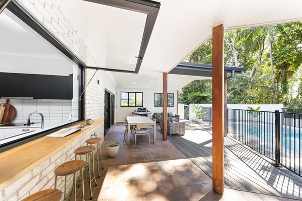Enjoy a spacious living area with a kitchen, dining, and seating space, connected to an outdoor deck with a pool.