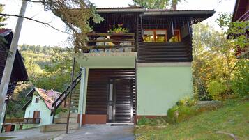 Situated in a wooded area, this cabin features a balcony and a small garden with a variety of plants.