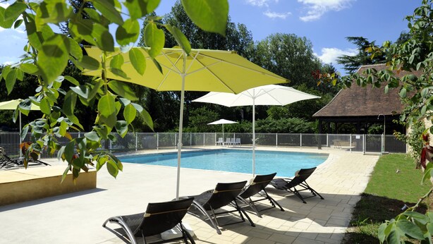 Un área de piscina con sillones de descanso y sombrillas.