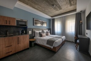 Habitación de hotel moderna con kitchenette, una cama grande, un escritorio y vistas al exterior.