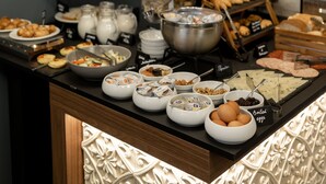 A buffet with various food items and condiments, including bowls of eggs, a fruit display, and a coffee station. - Marea Boutique Hotels (Sliema)