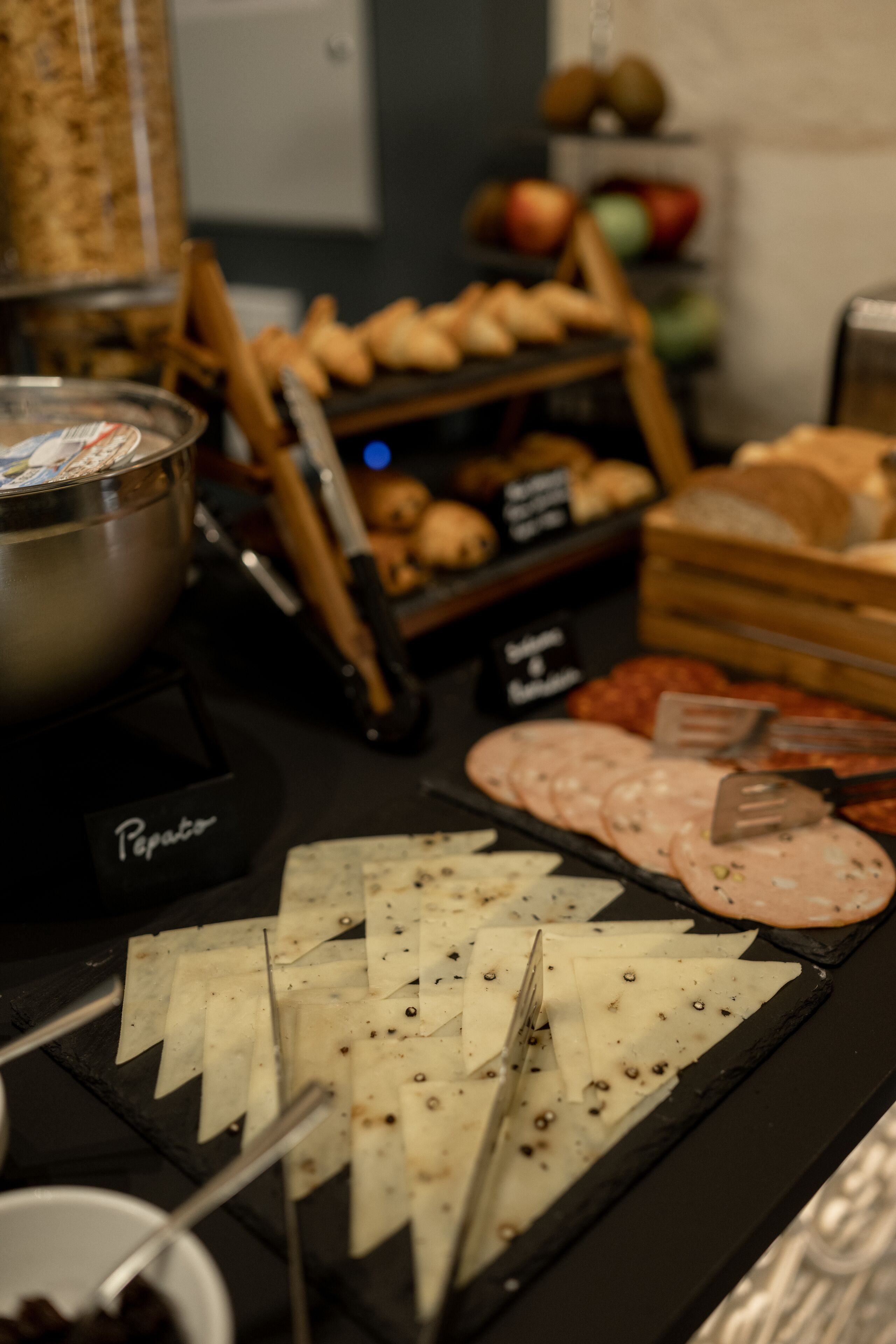A buffet with various food items including sliced meats, cheeses, and pastries.