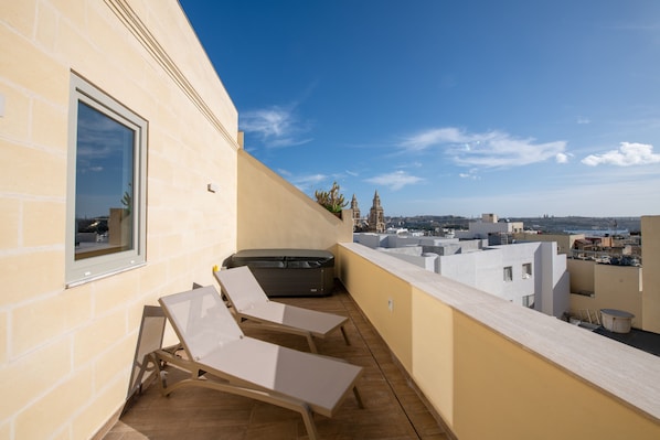 A rooftop terrace with two lounge chairs, a hot tub, and a view of the cityscape. - Marea Boutique Hotels (Sliema)