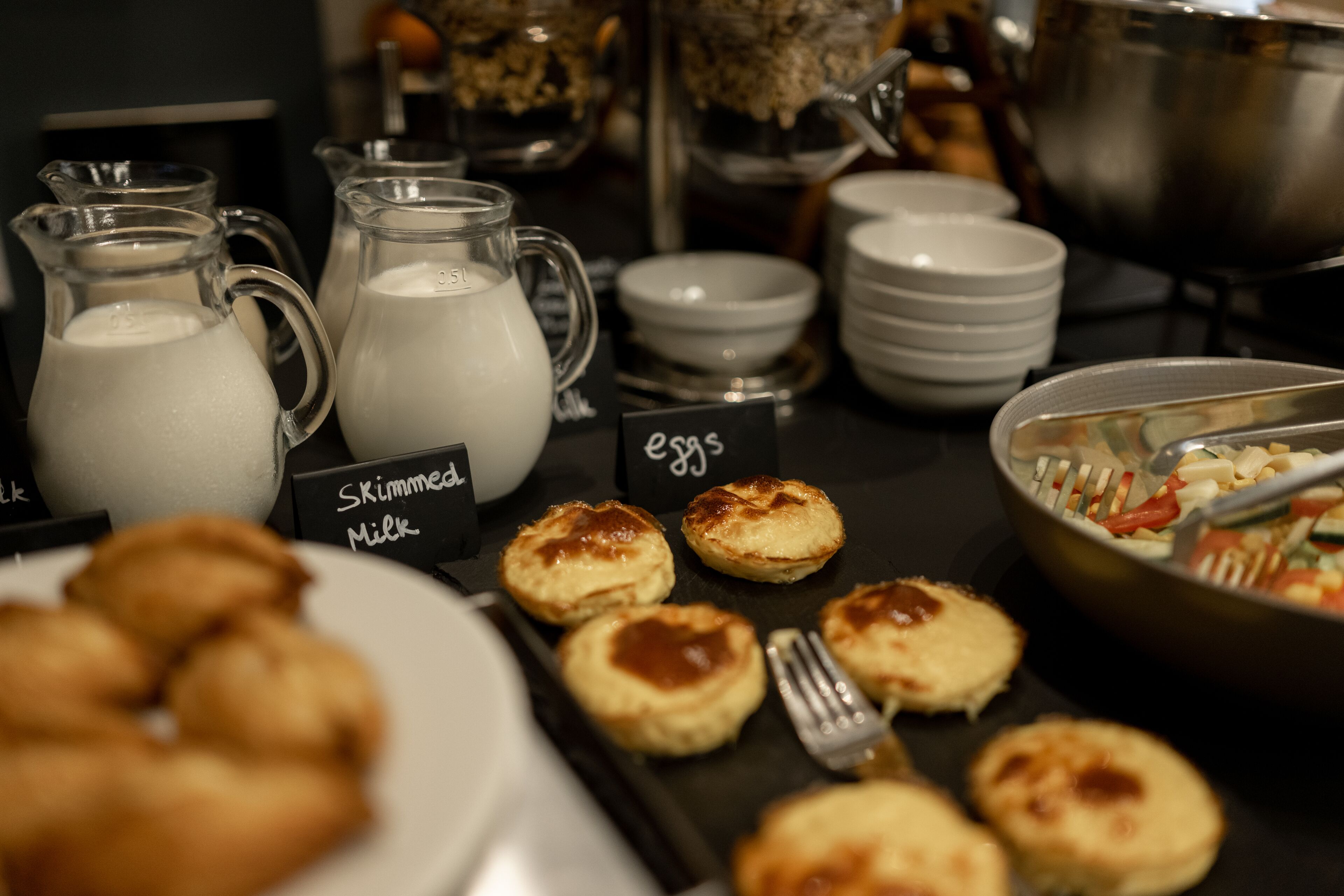 Un bufé con diversos alimentos, incluyendo pasteles y una jarra de leche.