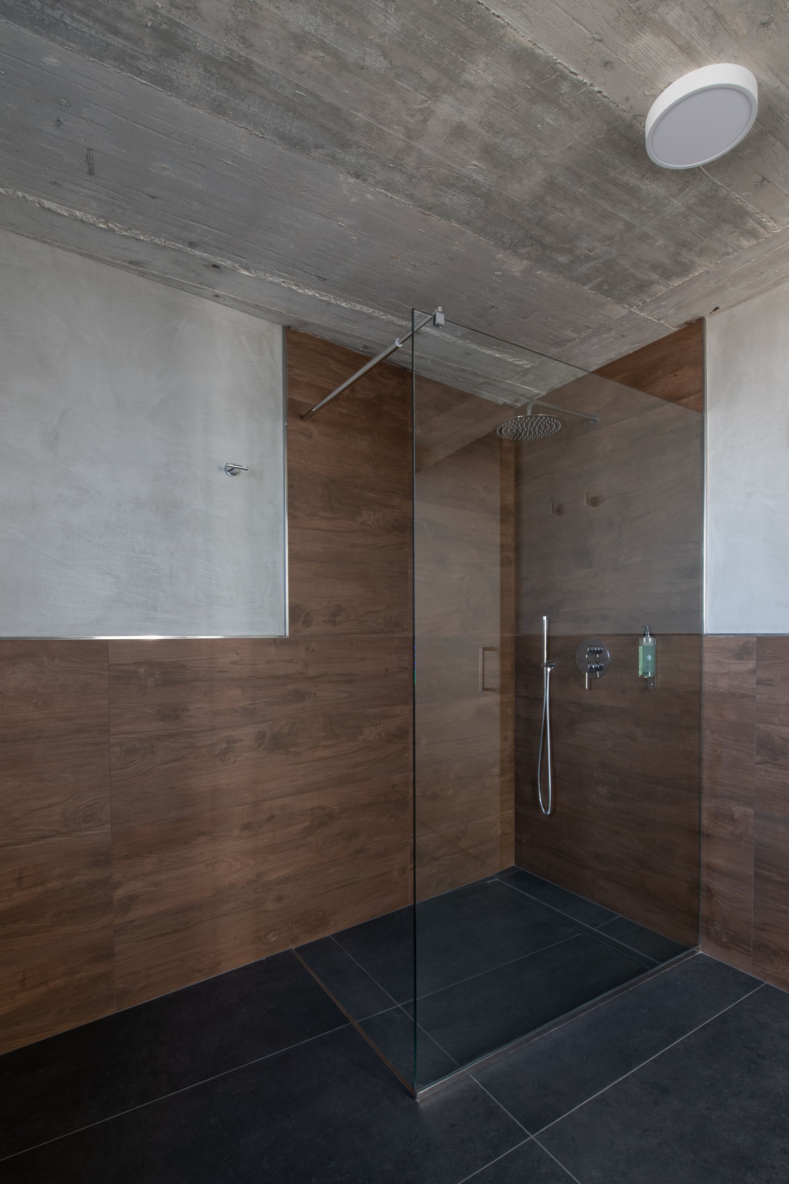 Ein modernes Duschbad mit Glastür, Handbrause und am Wand montierter Armatur.