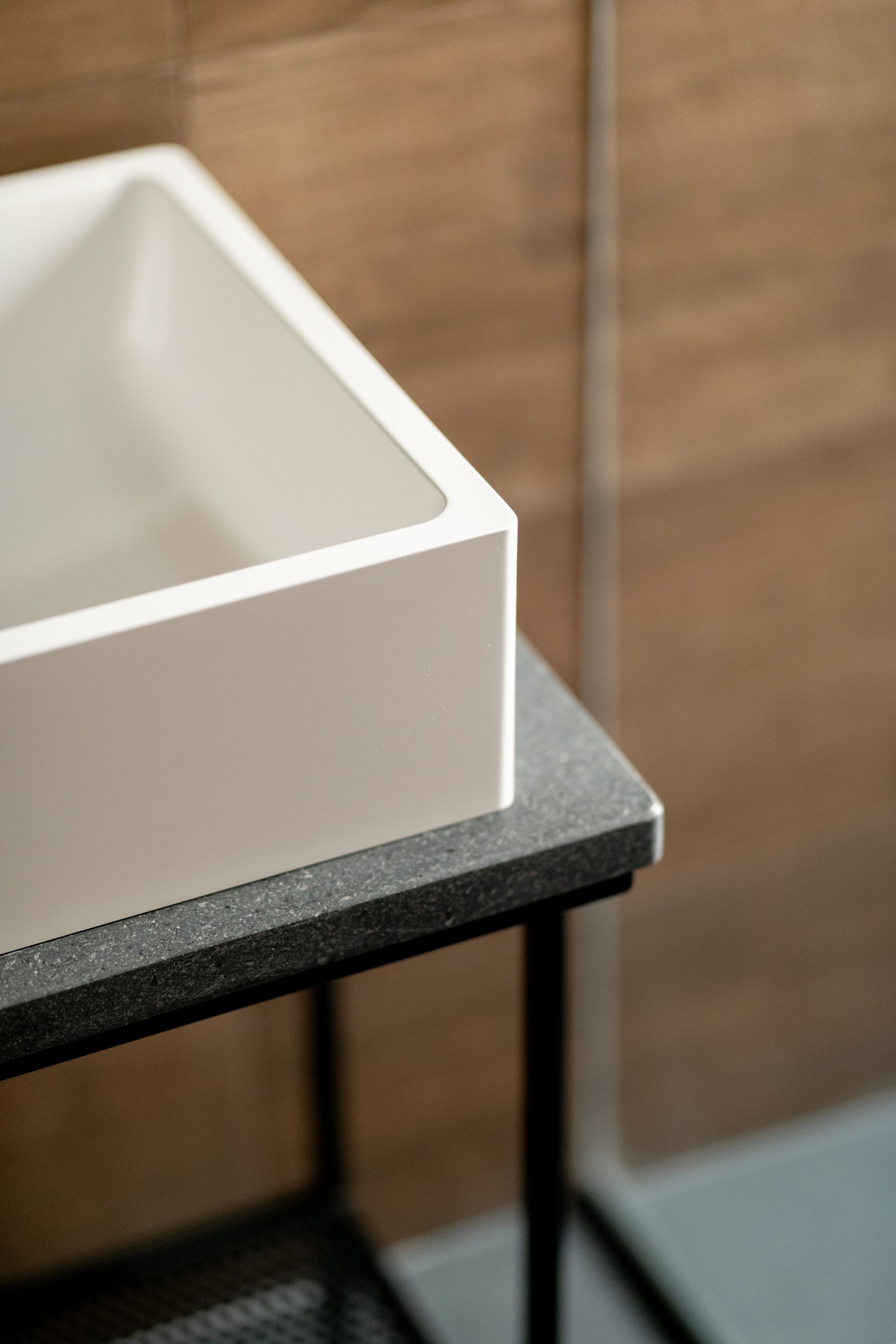 A white rectangular object on a dark surface, possibly a piece of furniture or equipment, against a wooden background.