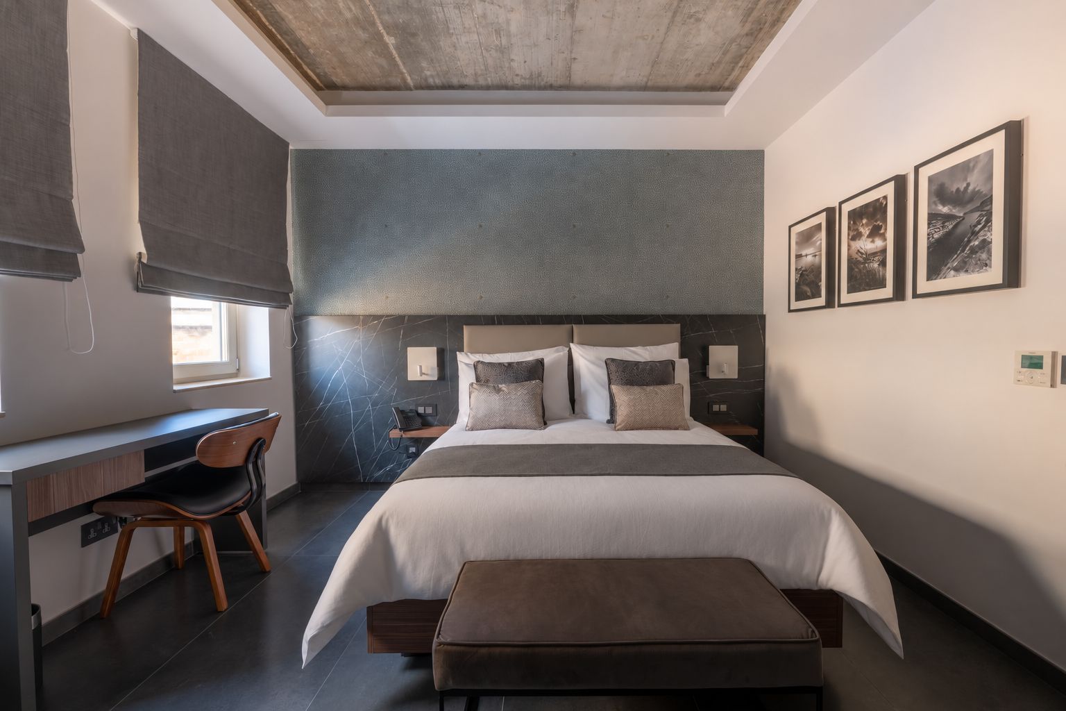 A modern bedroom with a bed, desk, chair, and artwork on the wall.