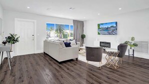 A modern living room with a sofa, chairs, a dining table, and a TV.