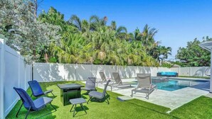Un jardin avec une pelouse artificielle, une piscine et des chaises longues.