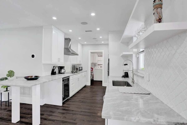 A modern kitchen with white cabinetry, a central island, and a built-in oven.