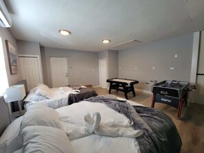 Een hotelkamer met twee bedden, een pooltafel en een tafelvoetbaltafel.