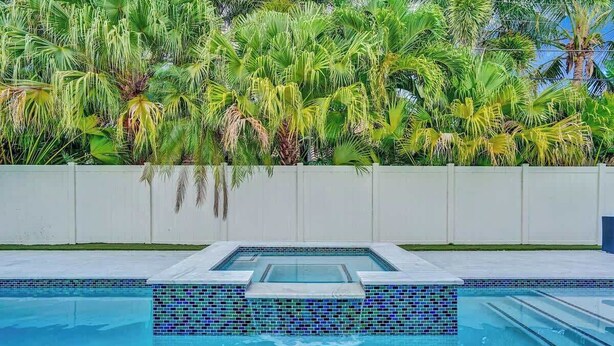 Une piscine avec un bord carrelé et un espace jacuzzi intégré.