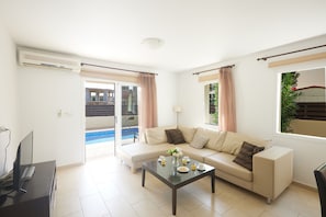 Ein modernes Wohnzimmer mit einer Couch, einem Couchtisch und einem Fernseher.