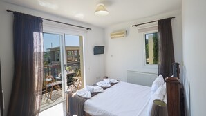 Een hotelkamer met een bed, gordijnen, een raam, een radiator en een televisietoestel.