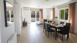 Een eethoek met een tafel voor vier personen, een bank en uitzicht op een balkon.