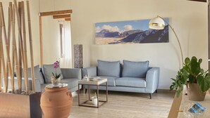 Un salon spacieux avec un plafond en bois, un canapé, une table basse et un grand tableau accroché au mur.