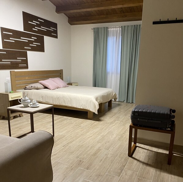 A bedroom with a bed, bedside table, and a suitcase on a stand.