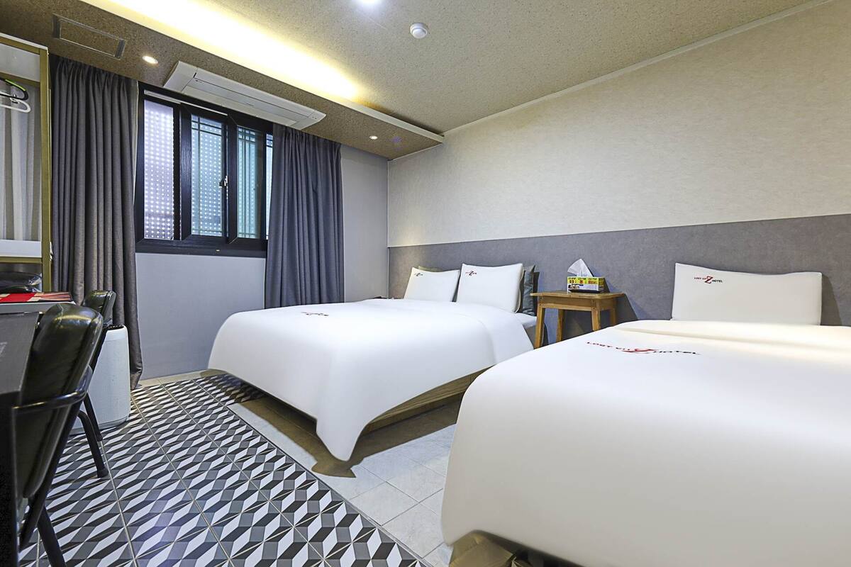 Habitación de hotel con dos camas, un escritorio y una silla.