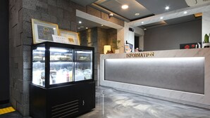 Un espace d’accueil doté d’un comptoir de réception en marbre portant l’inscription « RENSEIGNEMENTS » et d’un réfrigérateur noir à porte vitrée.