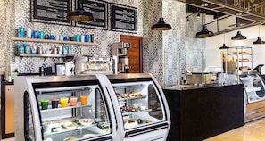 Ein Frühstücksbuffet mit einer Kaffeemaschine, einem Saftspender und einer Theke mit Speisen.