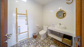 Une salle de bain équipée de toilettes, d’un lavabo, d’un miroir et de carreaux de sol à motifs.