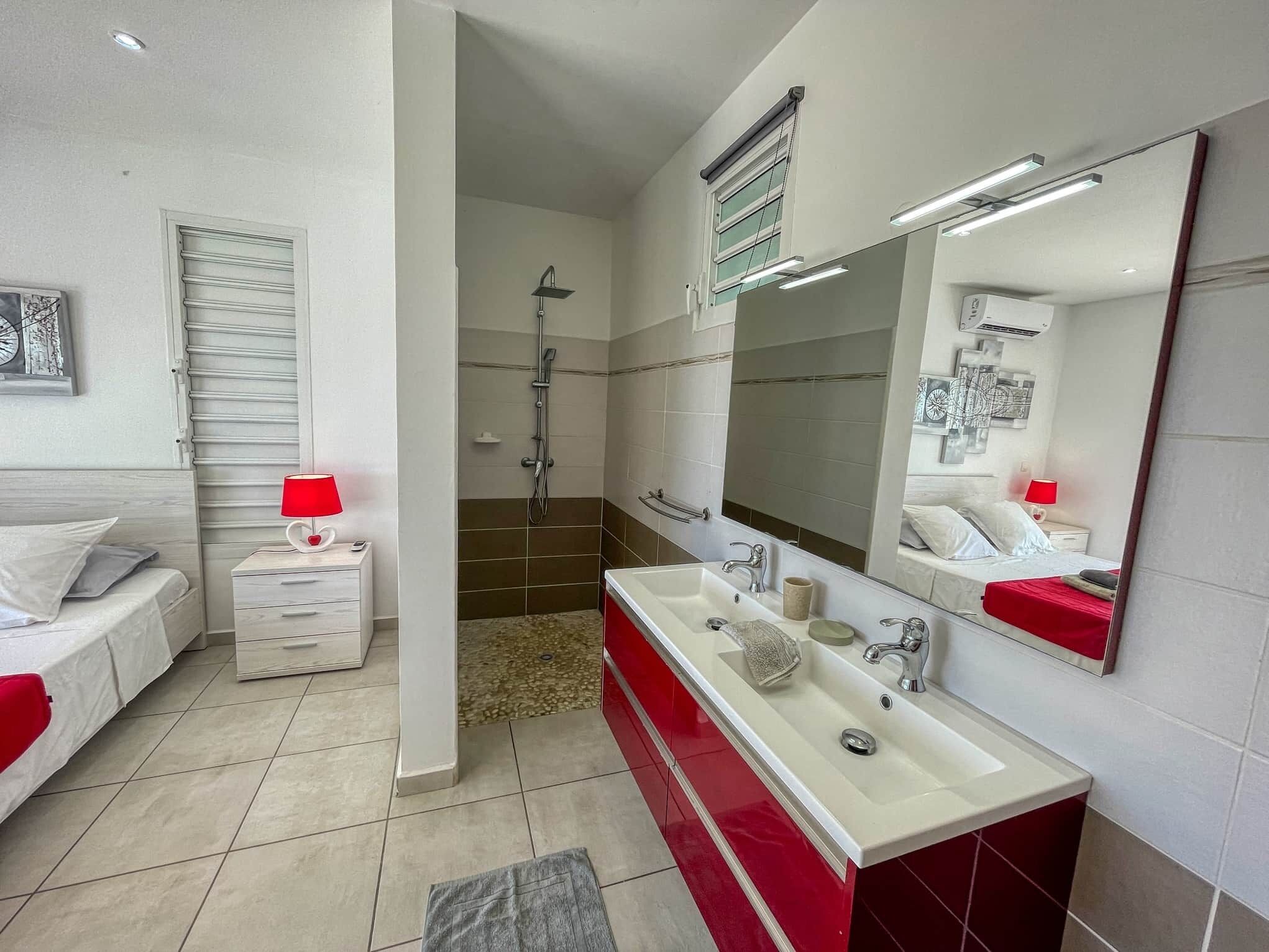 Ein modernes Badezimmer mit Dusche, großem Spiegel und Waschtisch.