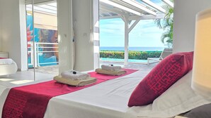 Une chambre d’hôtel avec un lit, une serviette rouge, un oreiller blanc et une vue sur l’océan.