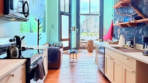 Una cocina con suelo de madera, un ventilador de techo y vistas a través de la puerta abierta.